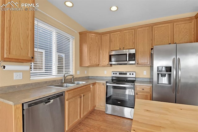 kitchen featuring wood counters, stainless steel appliances, light wood-type flooring, a sink, and recessed lighting