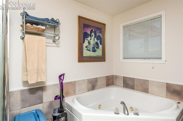 bathroom featuring a tub with jets and tile walls