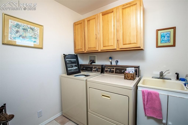 washroom with a sink, washing machine and clothes dryer, cabinet space, and baseboards