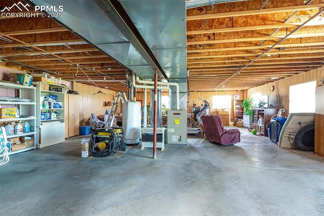 basement featuring water heater and wooden walls