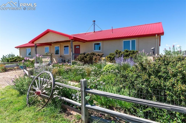 exterior space with metal roof, fence, and stucco siding