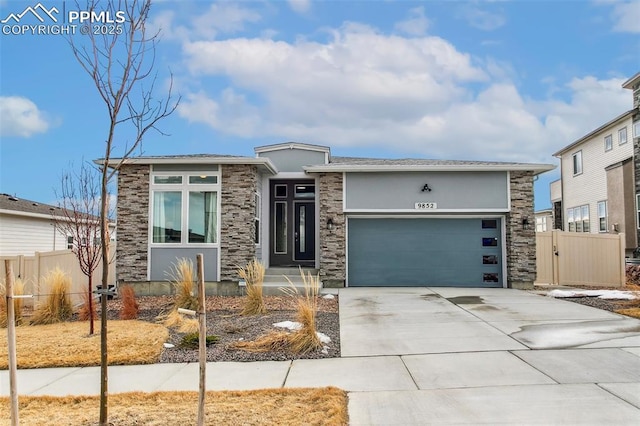 prairie-style house with driveway, stone siding, an attached garage, fence, and stucco siding