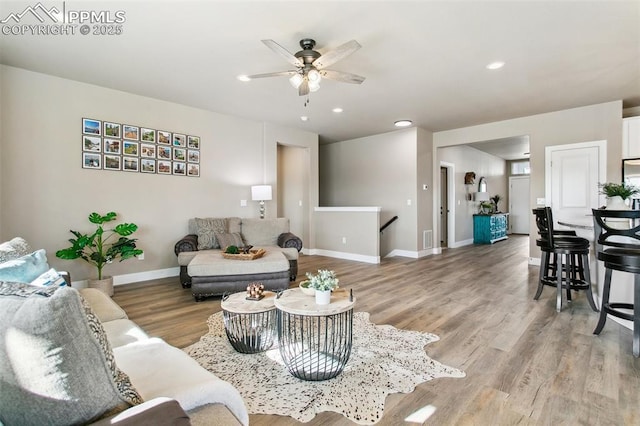 living room with recessed lighting, visible vents, baseboards, and wood finished floors