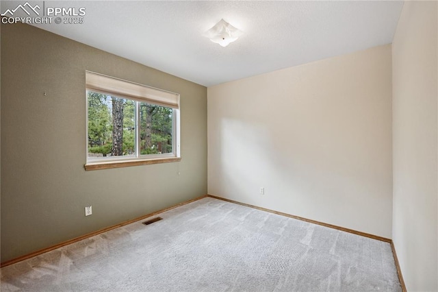 carpeted spare room with visible vents and baseboards