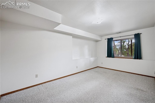 carpeted spare room featuring a textured ceiling and baseboards