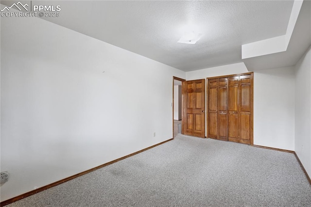 unfurnished bedroom featuring carpet, a textured ceiling, baseboards, and a closet