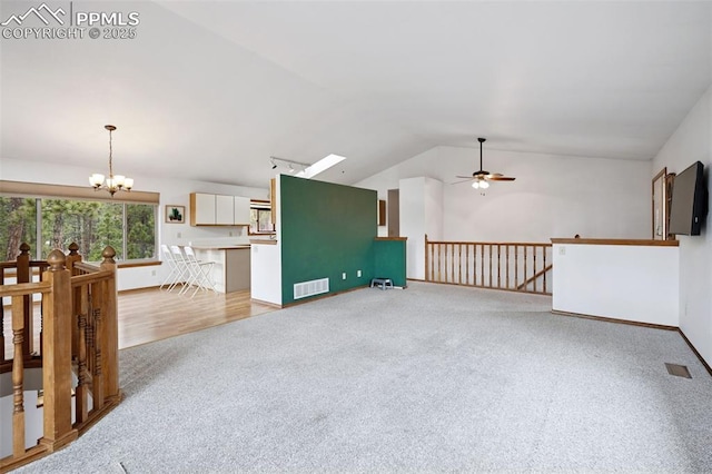 living area with light colored carpet, lofted ceiling, visible vents, and ceiling fan with notable chandelier