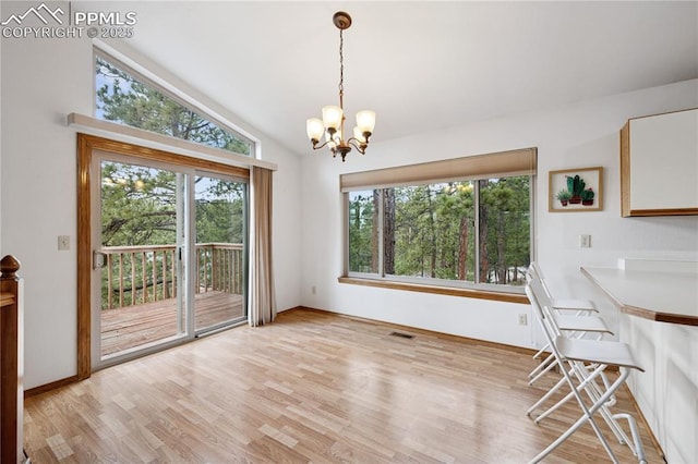 unfurnished dining area featuring visible vents, light wood-style floors, vaulted ceiling, a chandelier, and baseboards