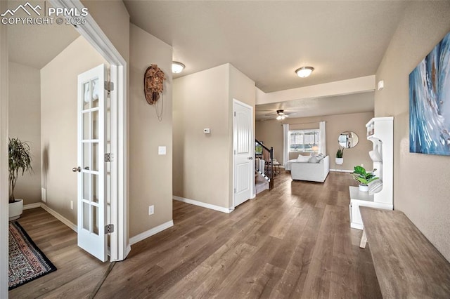 corridor with stairway, baseboards, wood finished floors, and french doors