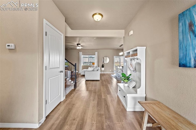 corridor featuring stairway, baseboards, and wood finished floors