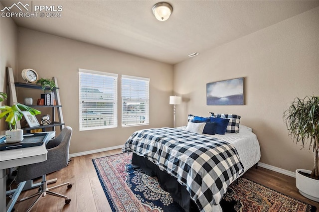 bedroom with visible vents, wood finished floors, and baseboards