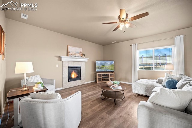 living area with wood finished floors, baseboards, visible vents, a fireplace, and ceiling fan