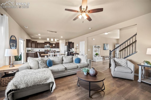 living area with baseboards, a ceiling fan, dark wood-style floors, and stairs