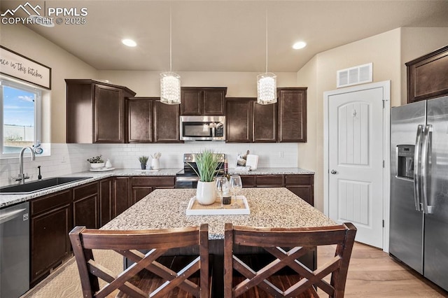 kitchen featuring visible vents, dark brown cabinets, backsplash, appliances with stainless steel finishes, and a sink