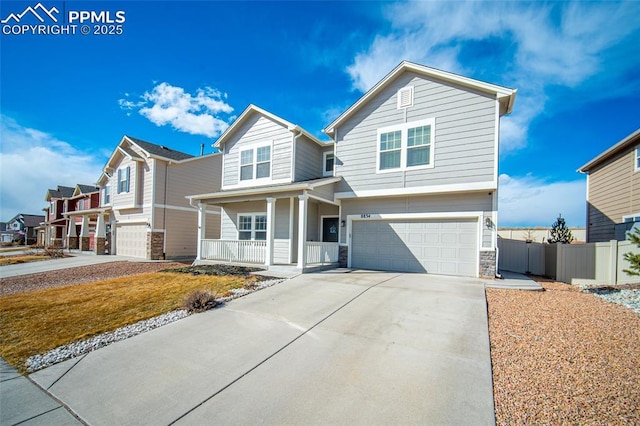 traditional home with stone siding, a porch, fence, concrete driveway, and an attached garage