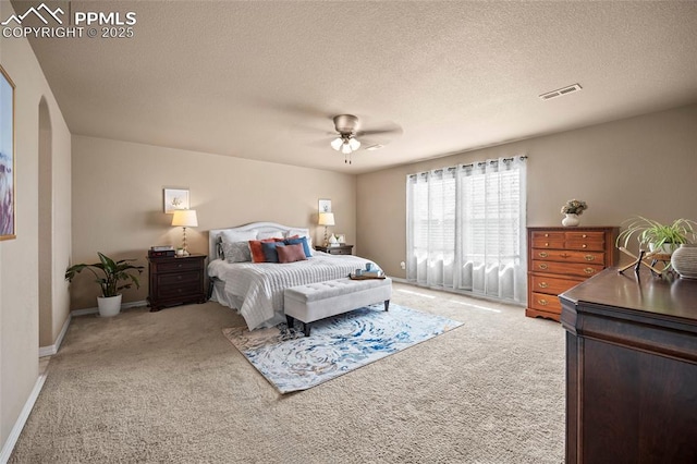 bedroom featuring ceiling fan, light colored carpet, visible vents, and a textured ceiling