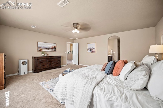 bedroom featuring visible vents, a ceiling fan, arched walkways, baseboards, and light colored carpet