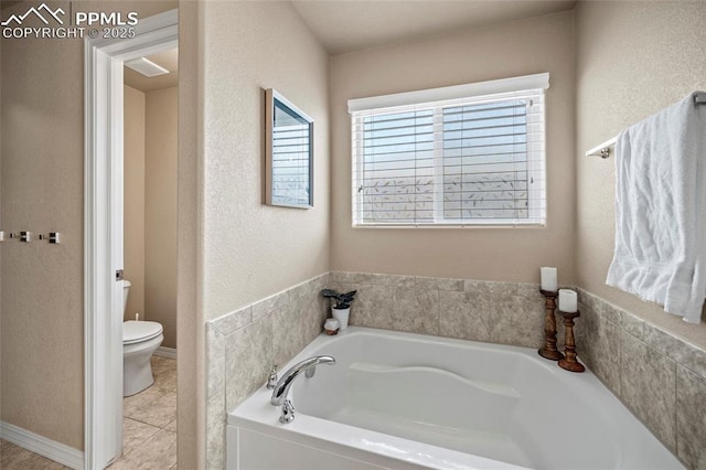 full bathroom featuring tile patterned flooring, toilet, a bath, and a textured wall