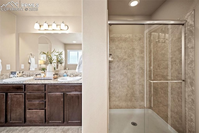 bathroom featuring a shower stall, double vanity, and a sink