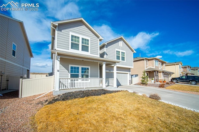 traditional home with a front yard, fence, driveway, covered porch, and a garage