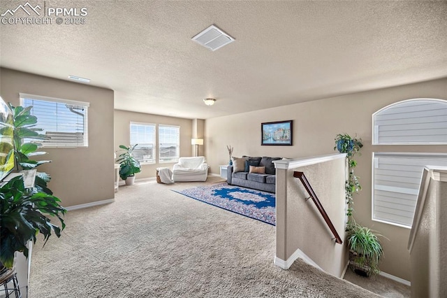 carpeted living area featuring visible vents, a textured ceiling, and baseboards