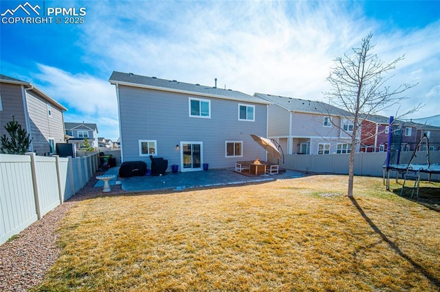 rear view of property with a patio, a yard, a fenced backyard, a trampoline, and a residential view