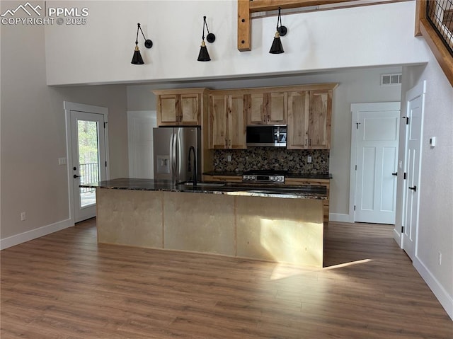 kitchen with visible vents, decorative backsplash, dark stone counters, stainless steel appliances, and a sink