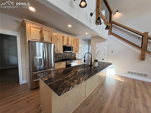 kitchen featuring visible vents, appliances with stainless steel finishes, a sink, an island with sink, and wood finished floors