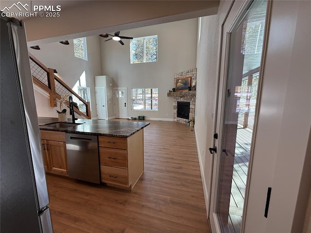 kitchen with appliances with stainless steel finishes, open floor plan, wood finished floors, a fireplace, and a sink