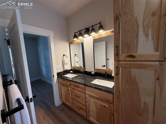 bathroom featuring wood finished floors, a sink, baseboards, and double vanity