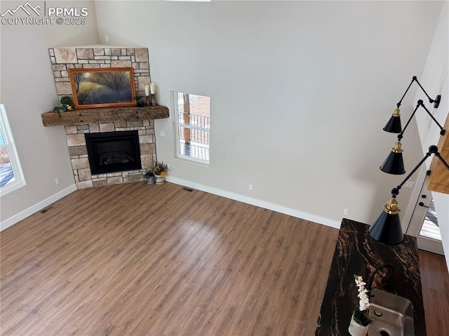 unfurnished living room featuring visible vents, a fireplace, baseboards, and wood finished floors