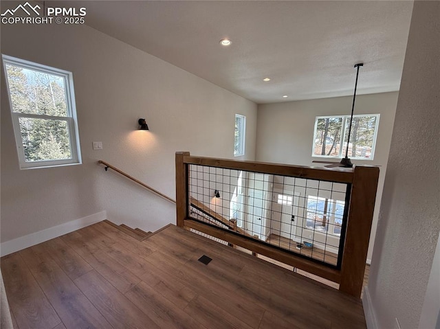 staircase with recessed lighting, a healthy amount of sunlight, baseboards, and wood finished floors