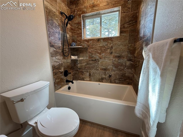 bathroom with toilet, shower / tub combination, wood finished floors, and a textured wall