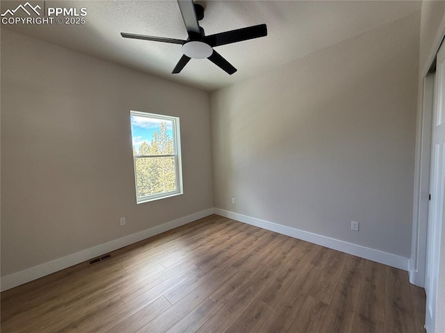 spare room featuring baseboards, visible vents, and wood finished floors