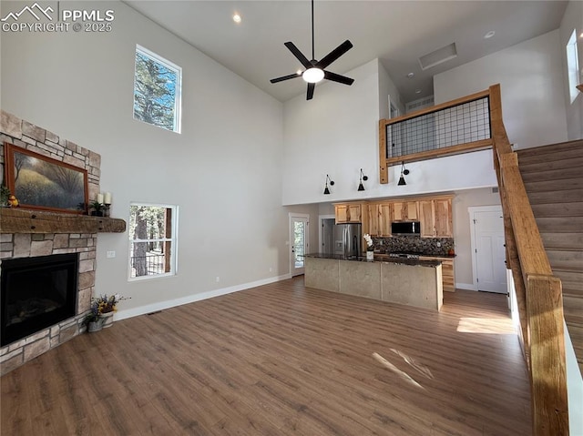 living area featuring dark wood-style flooring, plenty of natural light, and a stone fireplace