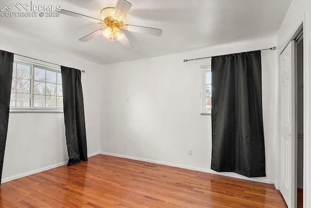 unfurnished room featuring a wealth of natural light, baseboards, ceiling fan, and light wood finished floors