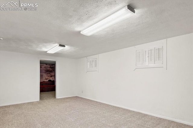 finished below grade area featuring carpet, a textured ceiling, and baseboards