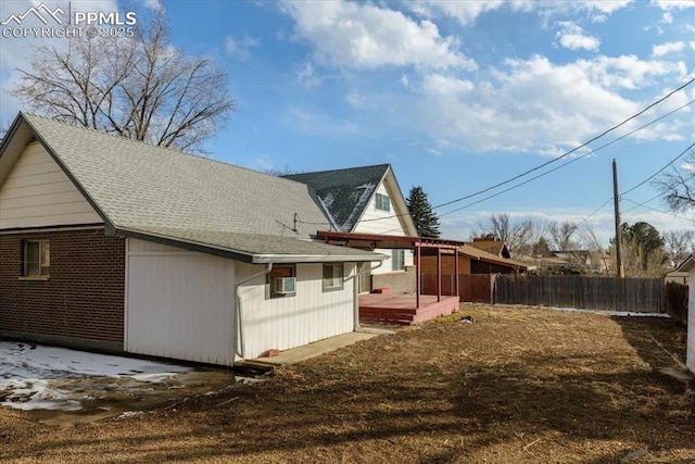 view of side of property featuring a shingled roof, fence, and a wooden deck