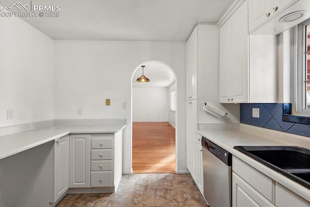 kitchen featuring light countertops, white cabinets, dishwasher, and arched walkways