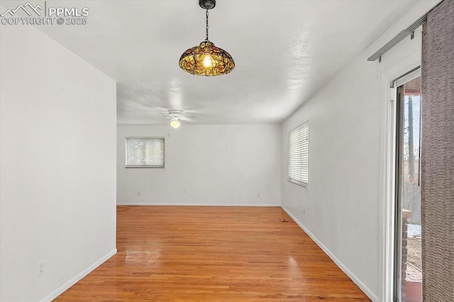 unfurnished room with light wood-style flooring, baseboards, and a ceiling fan