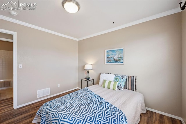 bedroom featuring baseboards, wood finished floors, visible vents, and crown molding