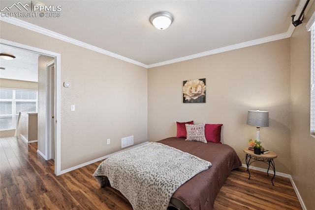 bedroom with baseboards, wood finished floors, visible vents, and crown molding