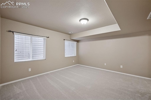 unfurnished room with visible vents, a textured ceiling, baseboards, and carpet flooring