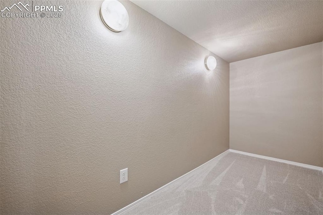 interior space featuring carpet flooring, a textured wall, a textured ceiling, and baseboards