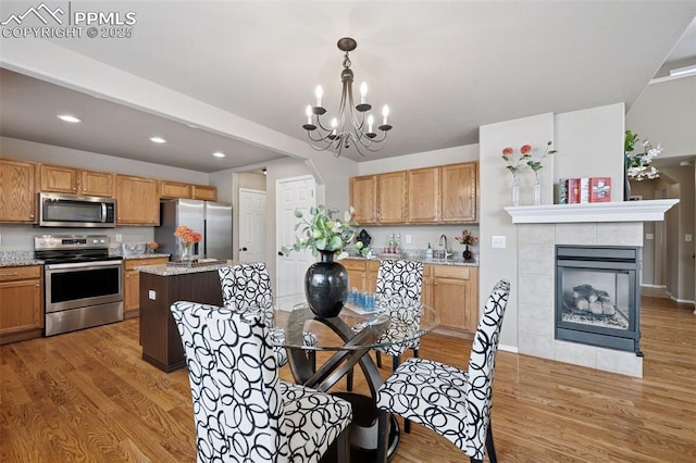 kitchen with decorative light fixtures, a notable chandelier, appliances with stainless steel finishes, light wood-style floors, and a kitchen island