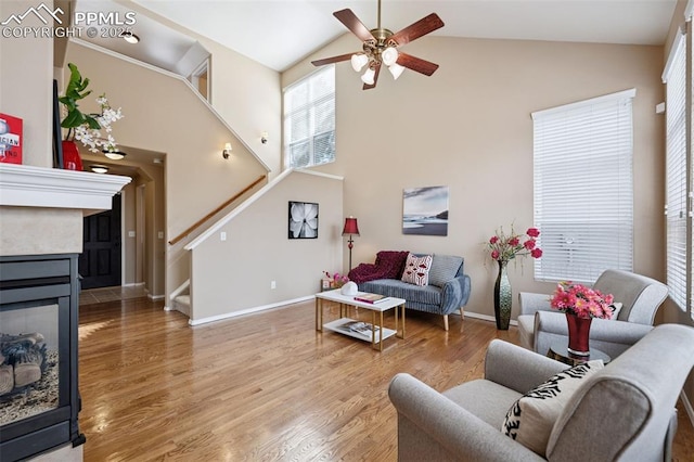 living room featuring high vaulted ceiling, a multi sided fireplace, baseboards, stairs, and light wood-style floors