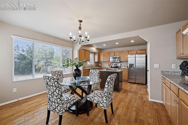 dining space with light wood-type flooring, baseboards, and a notable chandelier