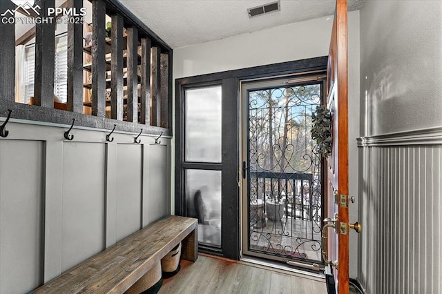 mudroom with a textured ceiling, visible vents, and light wood-style floors