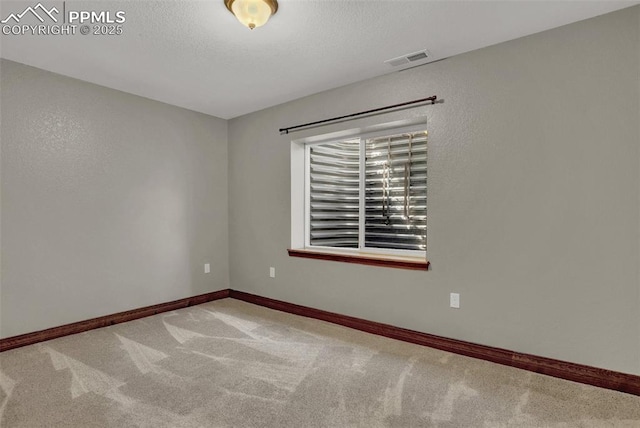 empty room featuring visible vents, light carpet, baseboards, and a textured ceiling