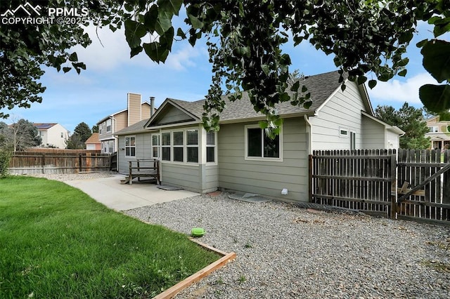 back of house with a yard, roof with shingles, a patio area, and a fenced backyard